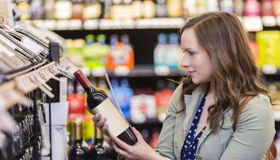 Pretty woman picking out wine at store