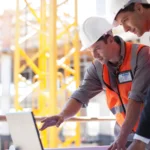 Two men looking at laptop on construction site
