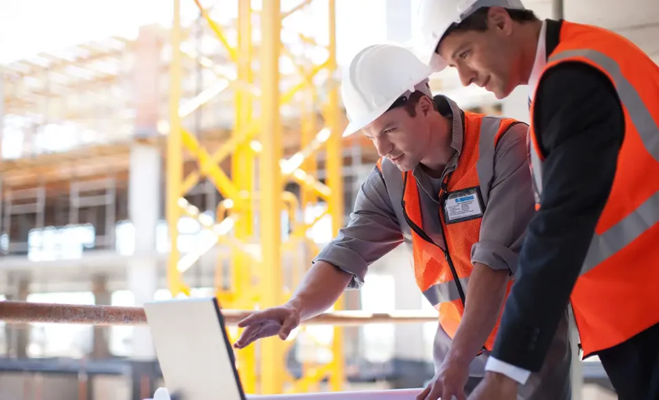 Two men looking at laptop on construction site