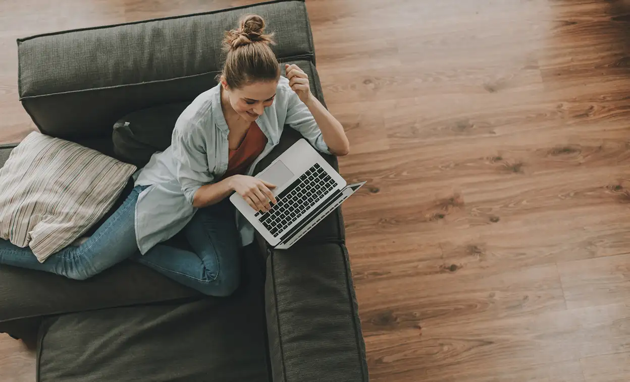 A woman sitting on a couch with her laptop