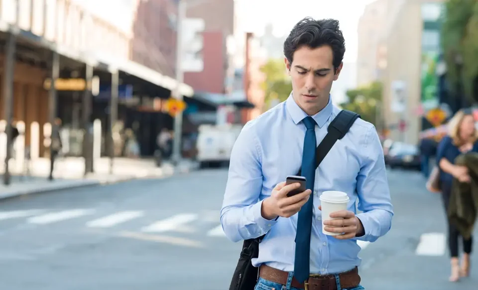 Man walking down street looking at mobile phone