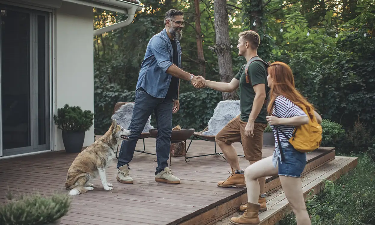 man and dog greeting guests on deck of his house