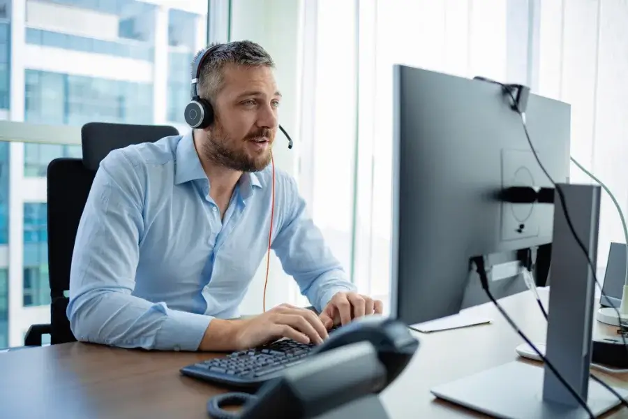 man in front of computer on the phone