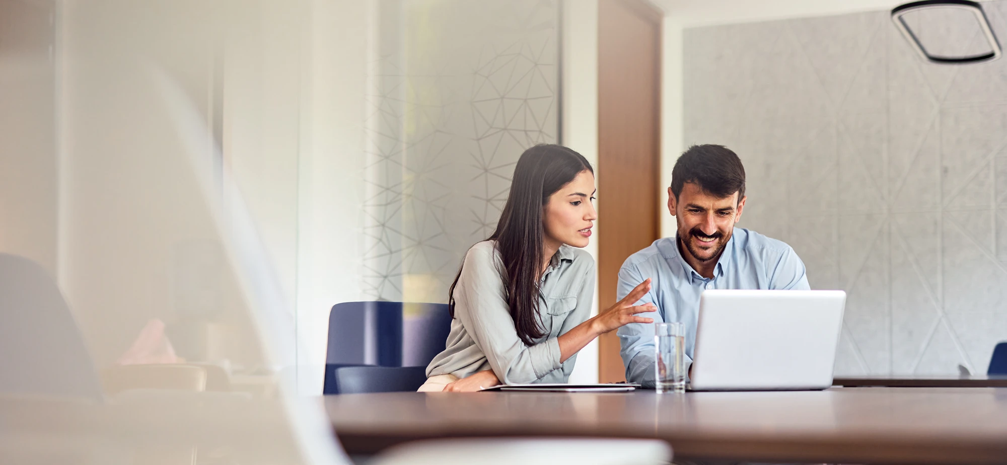 Two young professionals collaborate at a laptop.